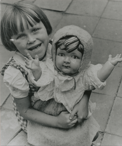 876871 Portret van Rietje Gijsen met een grote pop in de armen, vermoedelijk op de Kroonstraat in Wijk C te Utrecht, ...